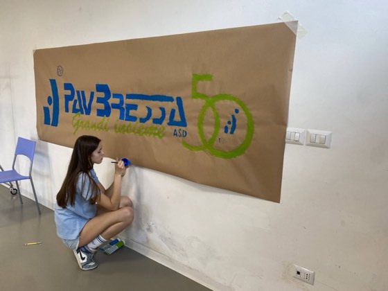 Una giovane atleta dipinge a mano lo striscione del 50° PavBressa