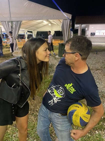 Un allenatore con il pallone e una giovane atleta si salutano durante la festa