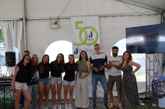 Premiazione di squadra davanti al logo dei 50 anni, 1976-2026