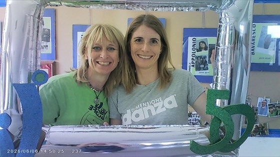 Due volontarie nella cornice del 50° davanti al muro delle fotografie storiche